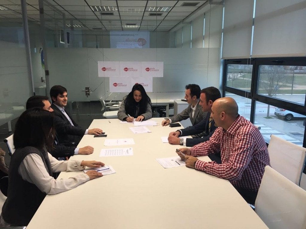 Reunión de varias personas en una sala con carteles de AJE Getafe Empresarial al fondo