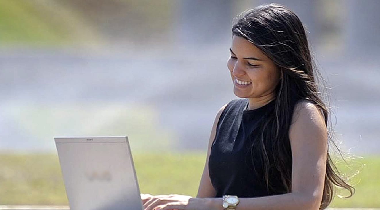 Mujer sonriente trabajando al aire libre con su portátil