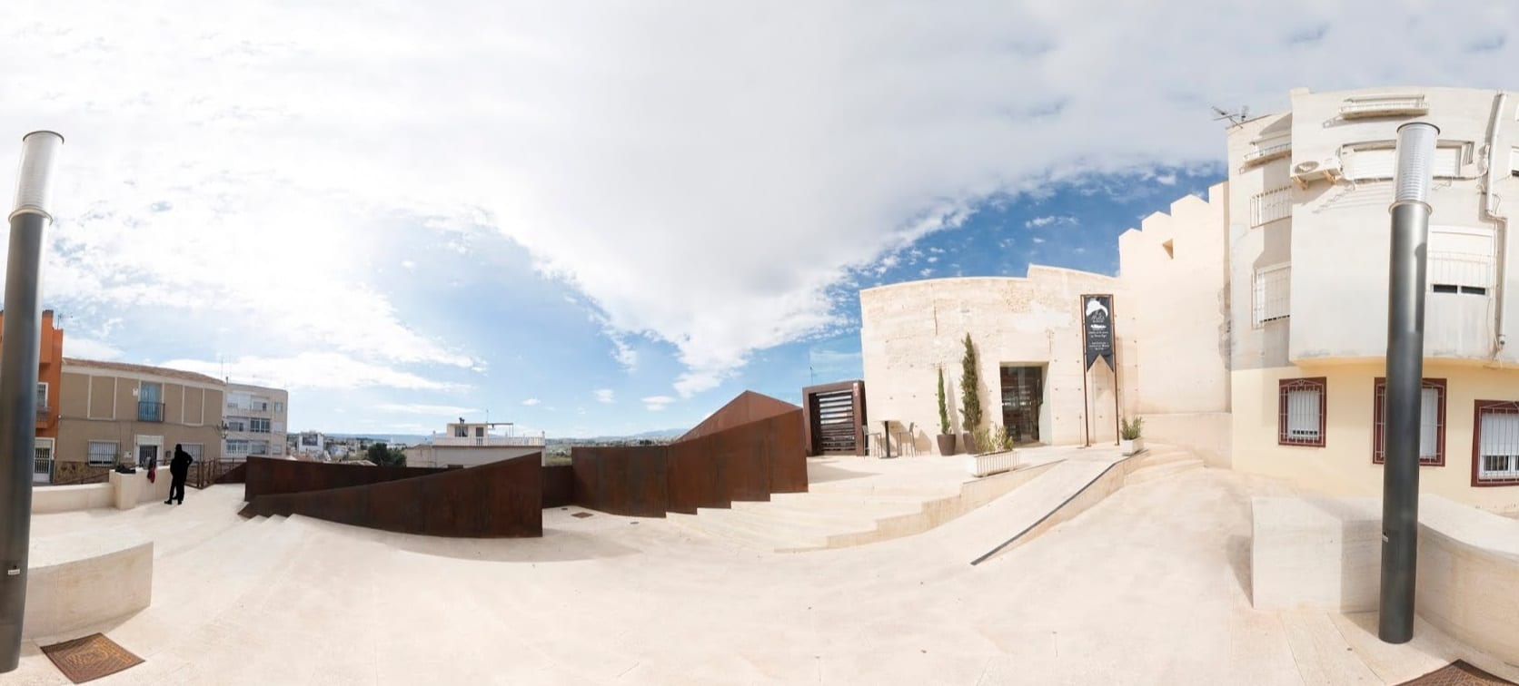 Plaza moderna de Molina de Segura con un muro de acero corten y el edificio del museo arqueológico al fondo