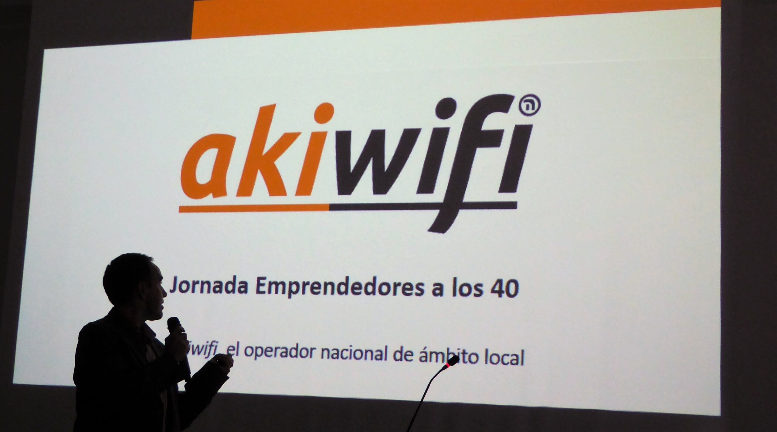 Ponente a contraluz ante una pantalla con el logo de akiwifi y el título «Jornada Emprendedores a los 40»