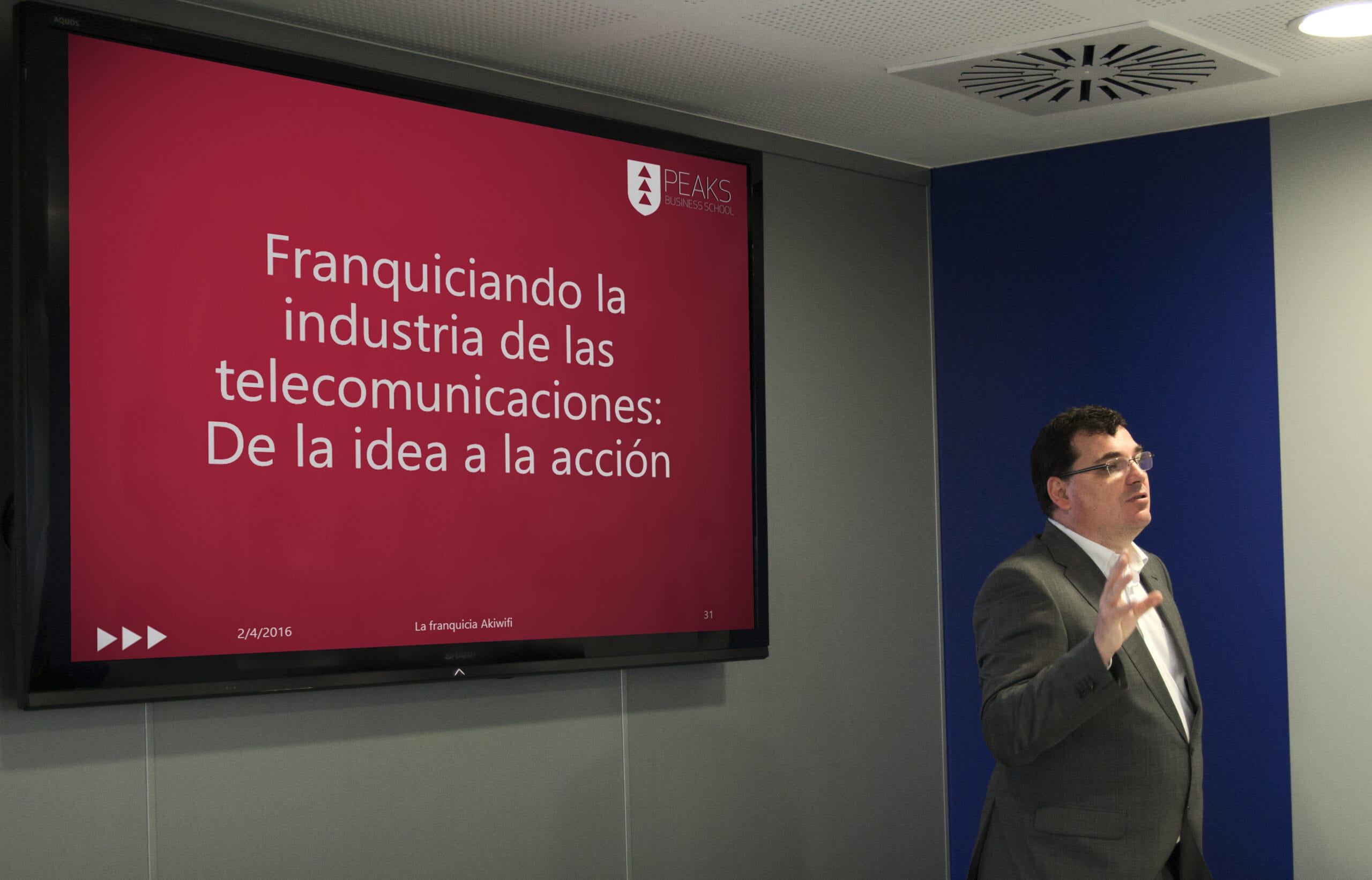 Ponente de akiwifi ante una pantalla con el título «Franquiciando la industria de las telecomunicaciones» en una jornada de PEAKS Business School