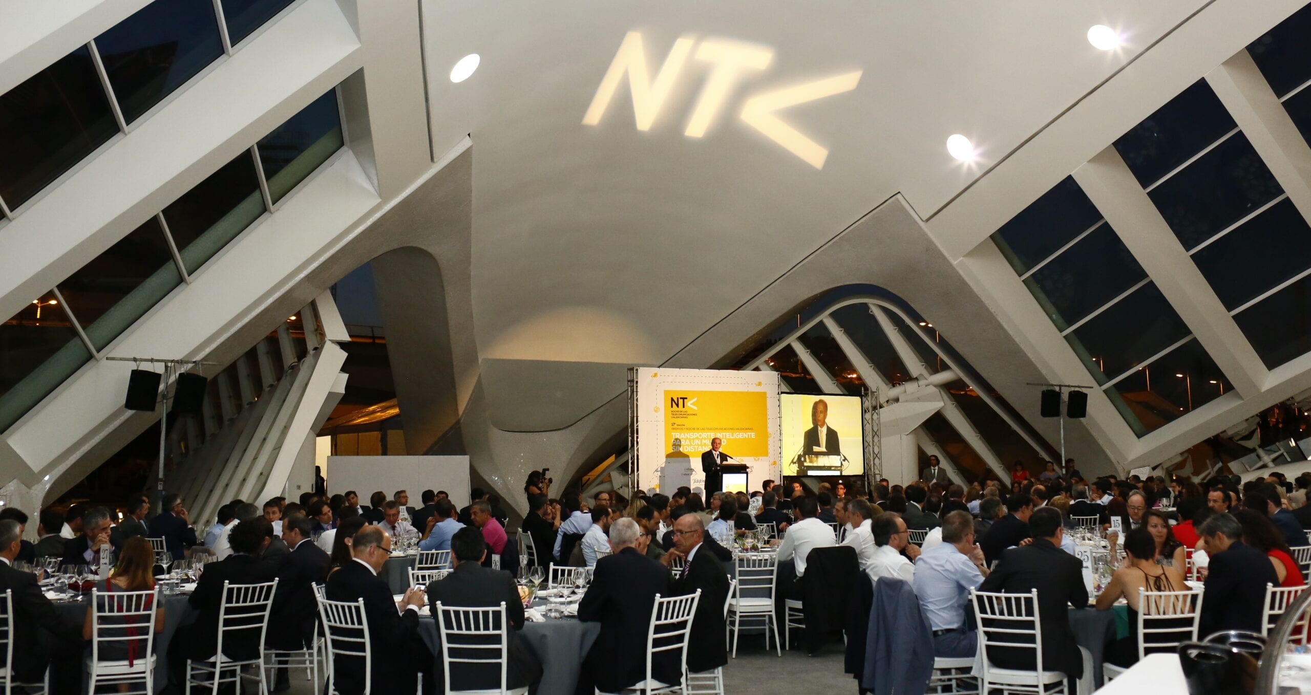 Público asistente a la gala de la Noche de las Telecomunicaciones Valencianas, con el logo NTC proyectado en el techo del recinto