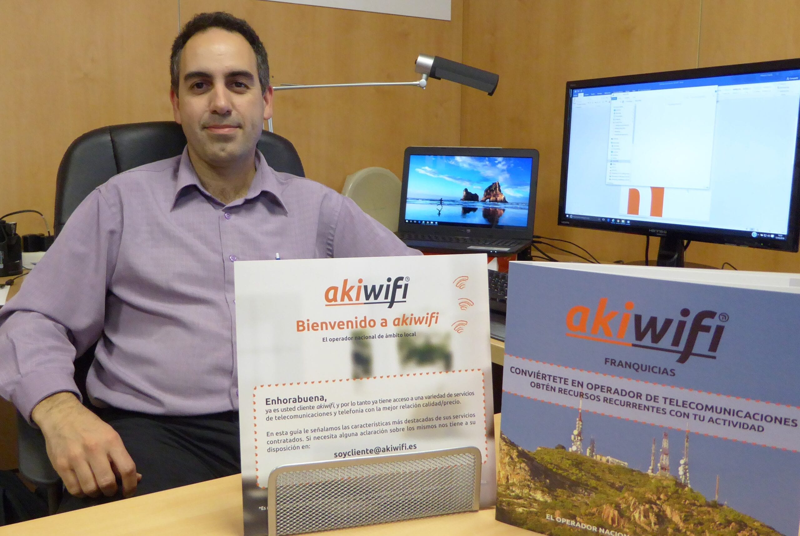 Hombre sentado en su despacho junto a folletos informativos de la franquicia akiwifi