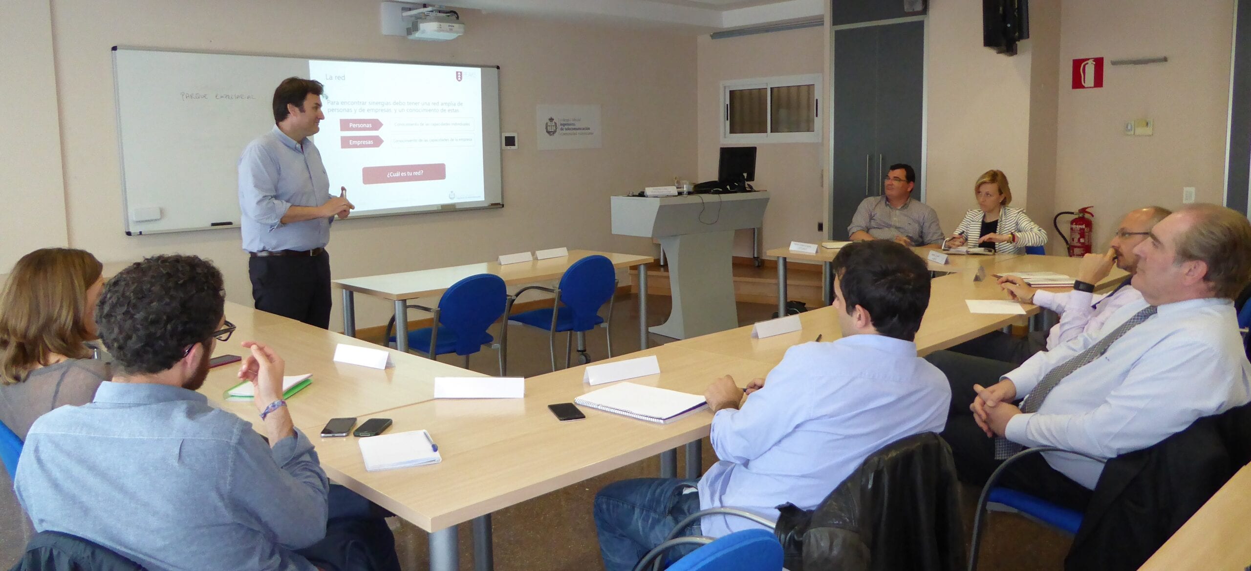 Ponente impartiendo una charla sobre trabajo en red ante un grupo sentado en una sala de reuniones