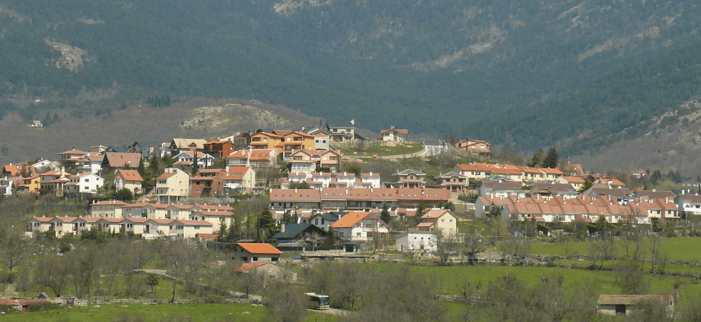 Vista de un municipio de la Sierra de Guadarrama con chalets entre montañas boscosas