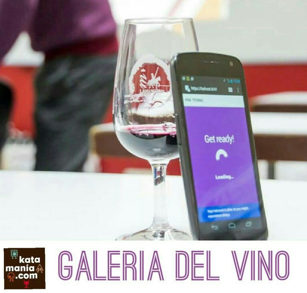 Copa de vino junto a un móvil con una aplicación de cata, cartel «Galería del Vino»