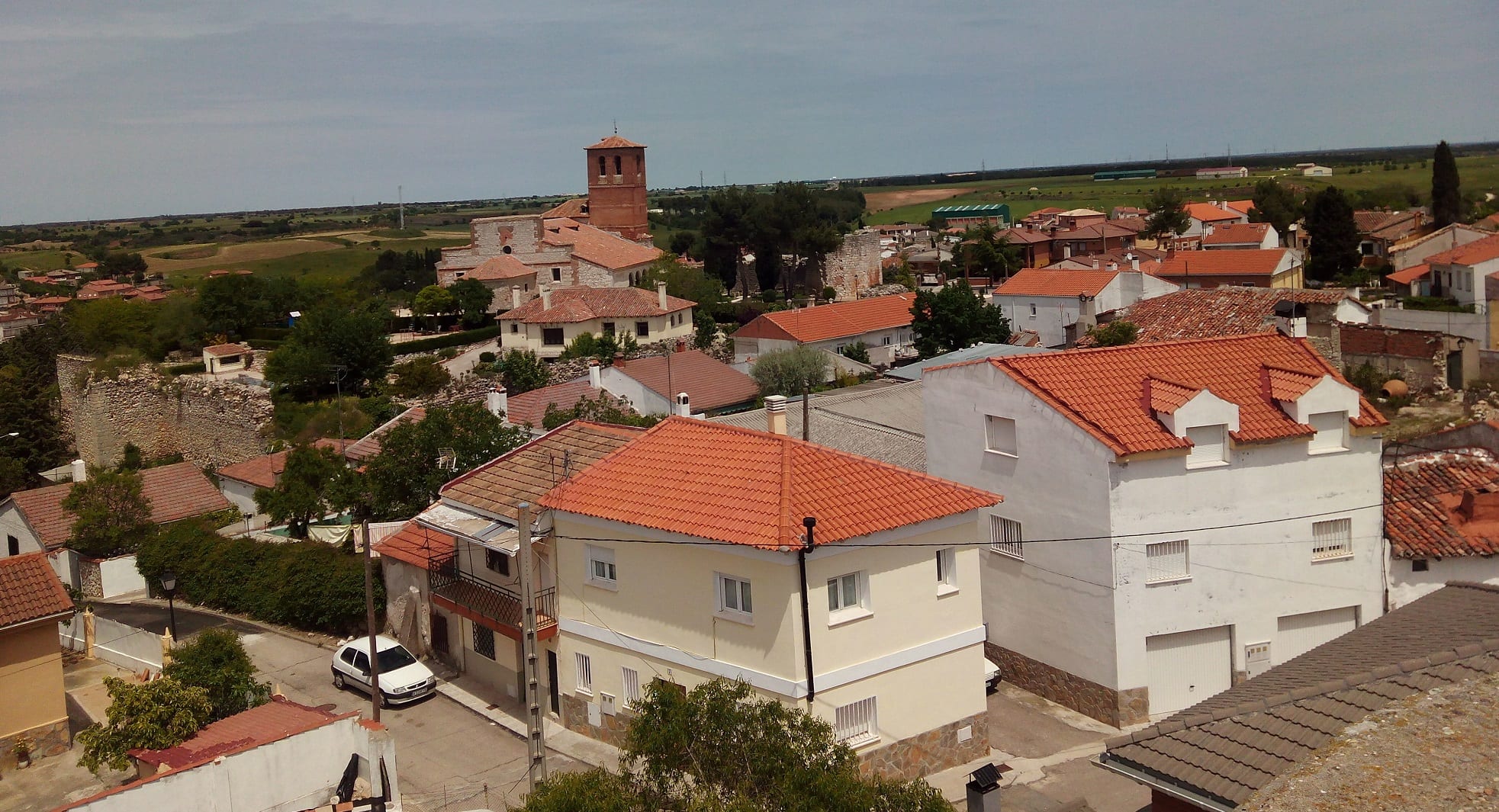 Vista aérea de un pueblo de la Alcarria con tejados de teja árabe y campos al fondo