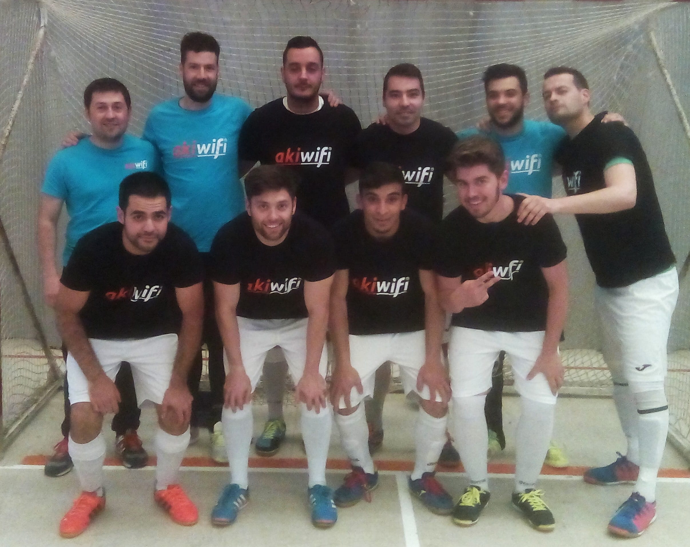 Equipo de fútbol sala con camiseta patrocinada por akiwifi, posando en la pista tras un partido