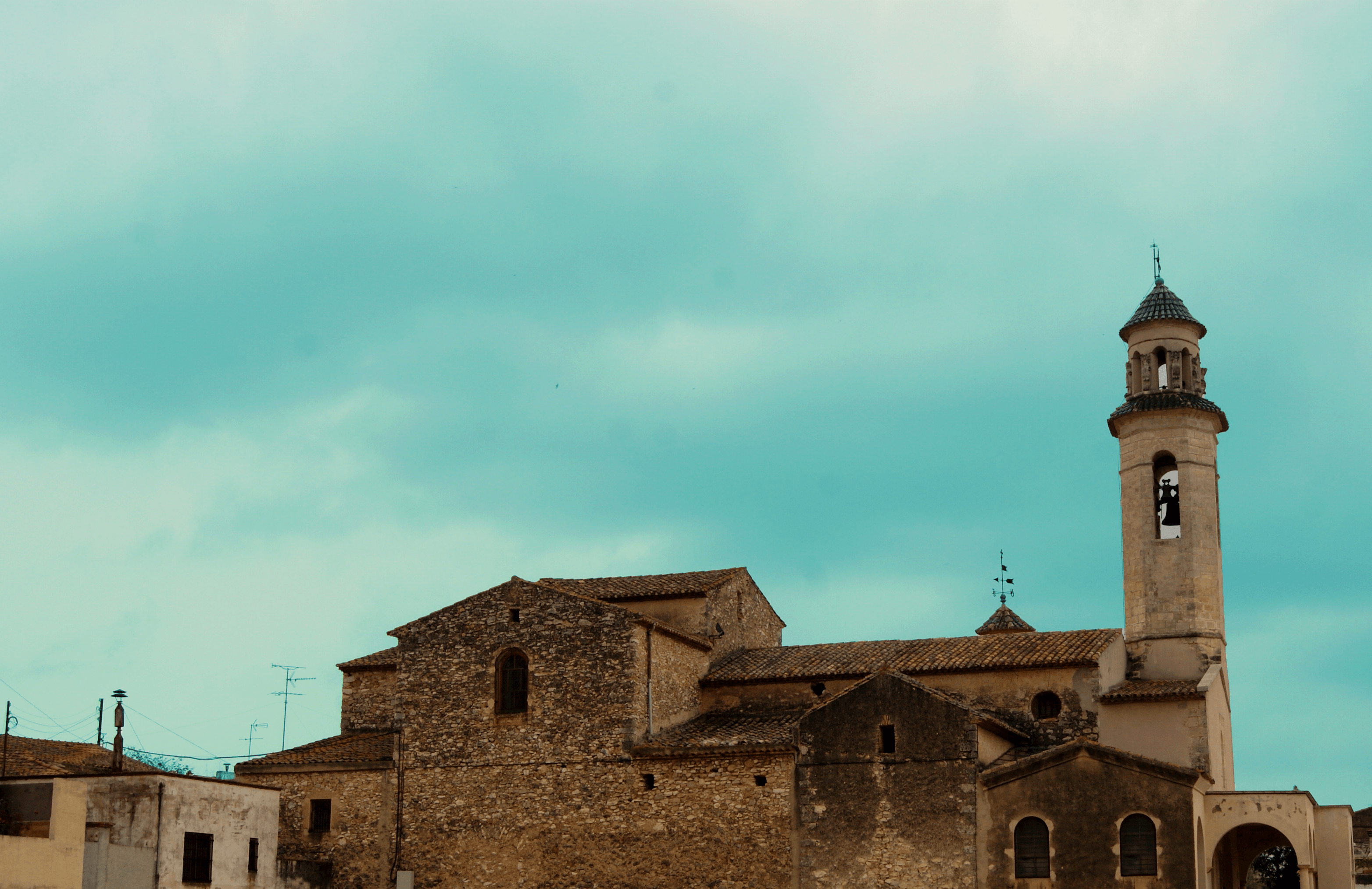 Campanario de una iglesia con el cielo en tonos turquesa