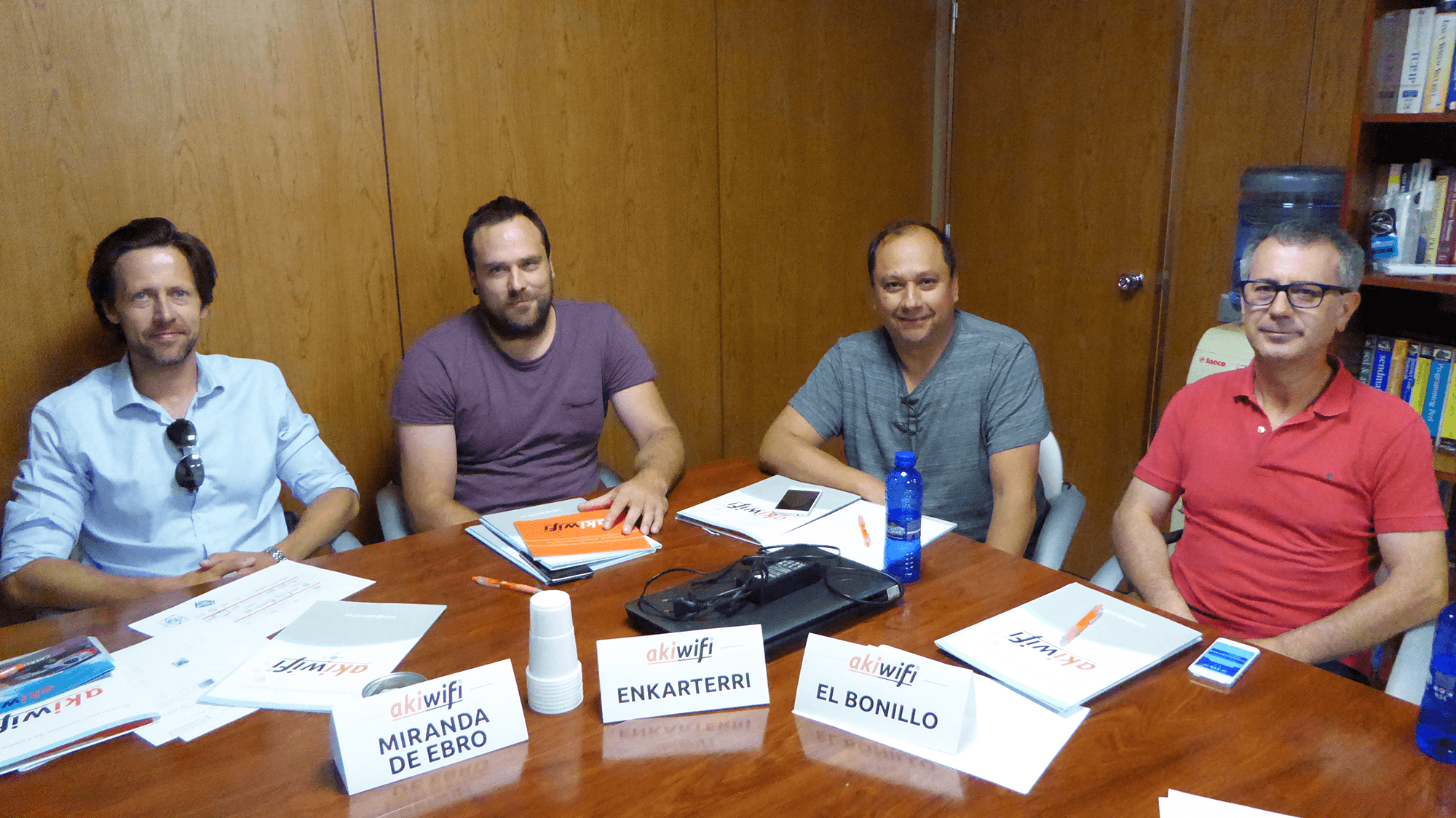 Cuatro franquiciados de akiwifi reunidos en una sala, con los carteles de sus zonas Miranda de Ebro, Enkarterri y El Bonillo sobre la mesa