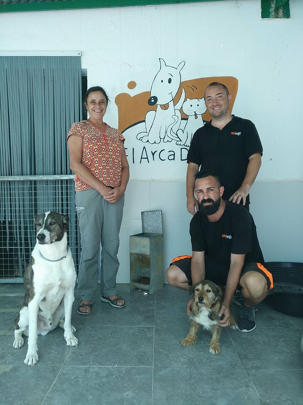 Dos técnicos de akiwifi junto a una voluntaria y dos perros en el refugio Arca de Noé