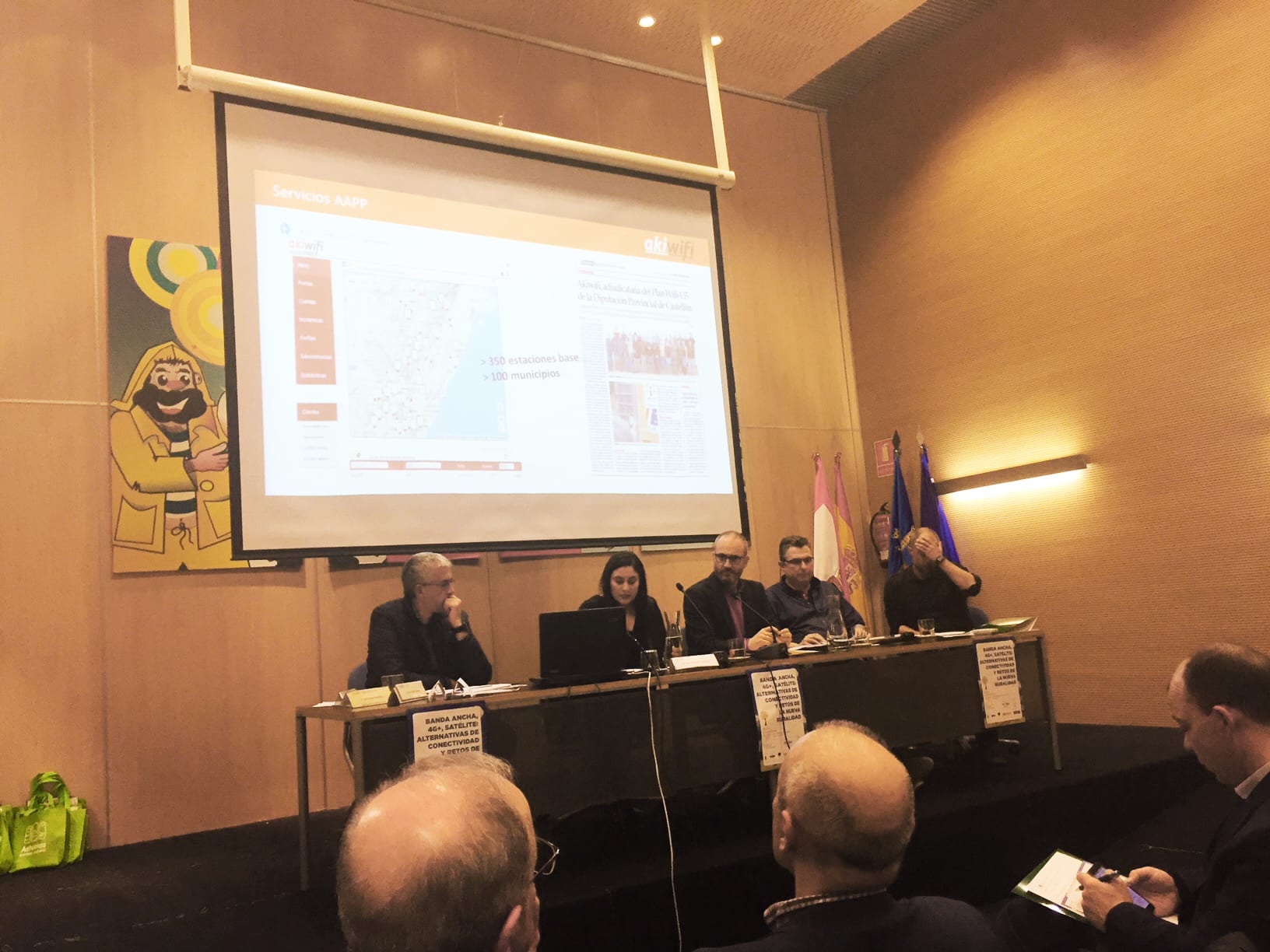 Ponentes en una mesa redonda sobre conectividad rural, con un mapa de cobertura de akiwifi proyectado en pantalla