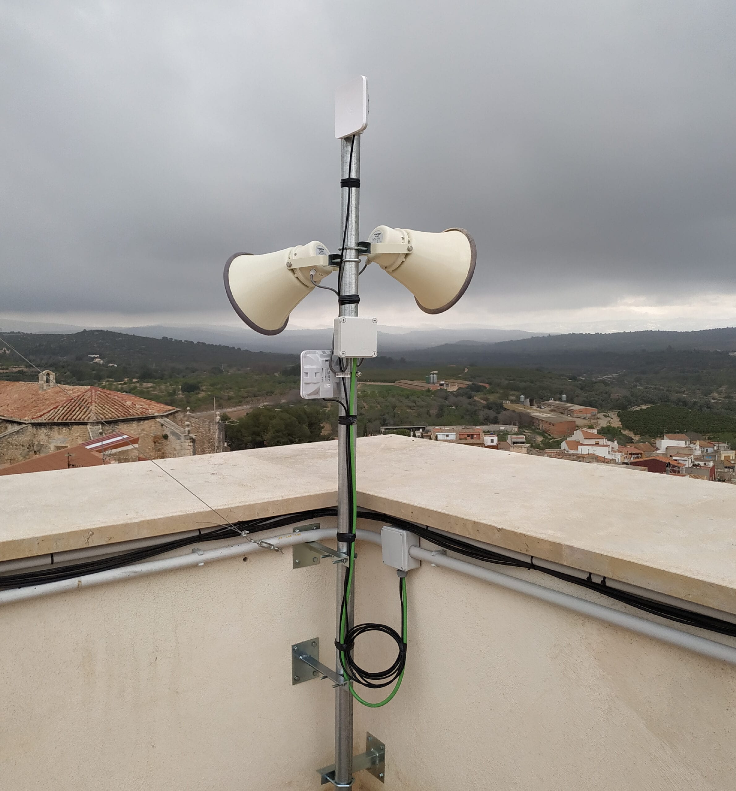 Antena y repetidores instalados en la azotea de un edificio de Càlig, con el pueblo y el campo al fondo