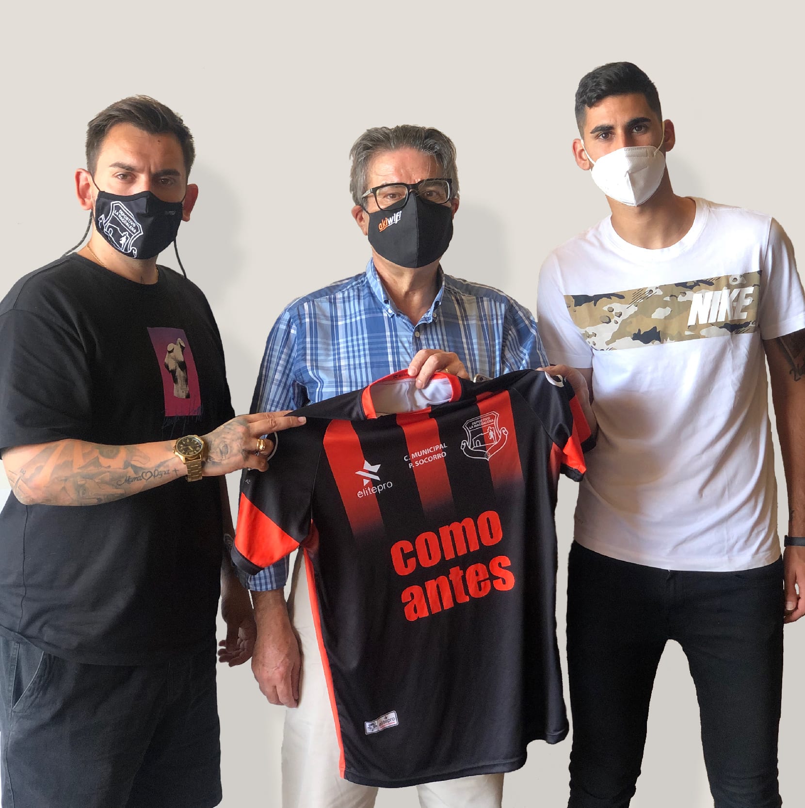 Tres hombres con mascarilla sosteniendo la camiseta del CD La Magdalena con el lema «Como antes»
