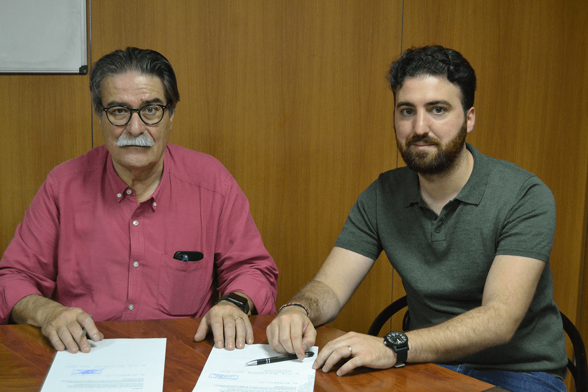 Dos hombres sentados a una mesa firmando un acuerdo de patrocinio