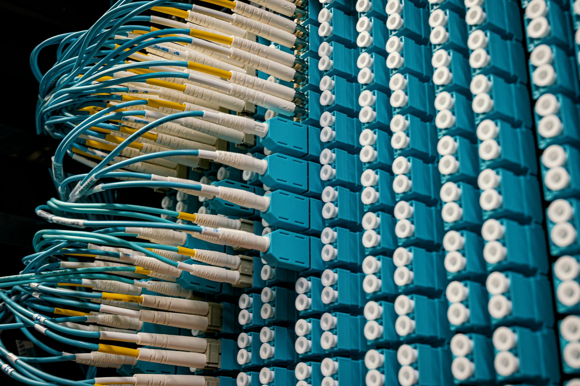 Panel de conexiones de fibra óptica con decenas de latiguillos conectados, típico de un centro de datos