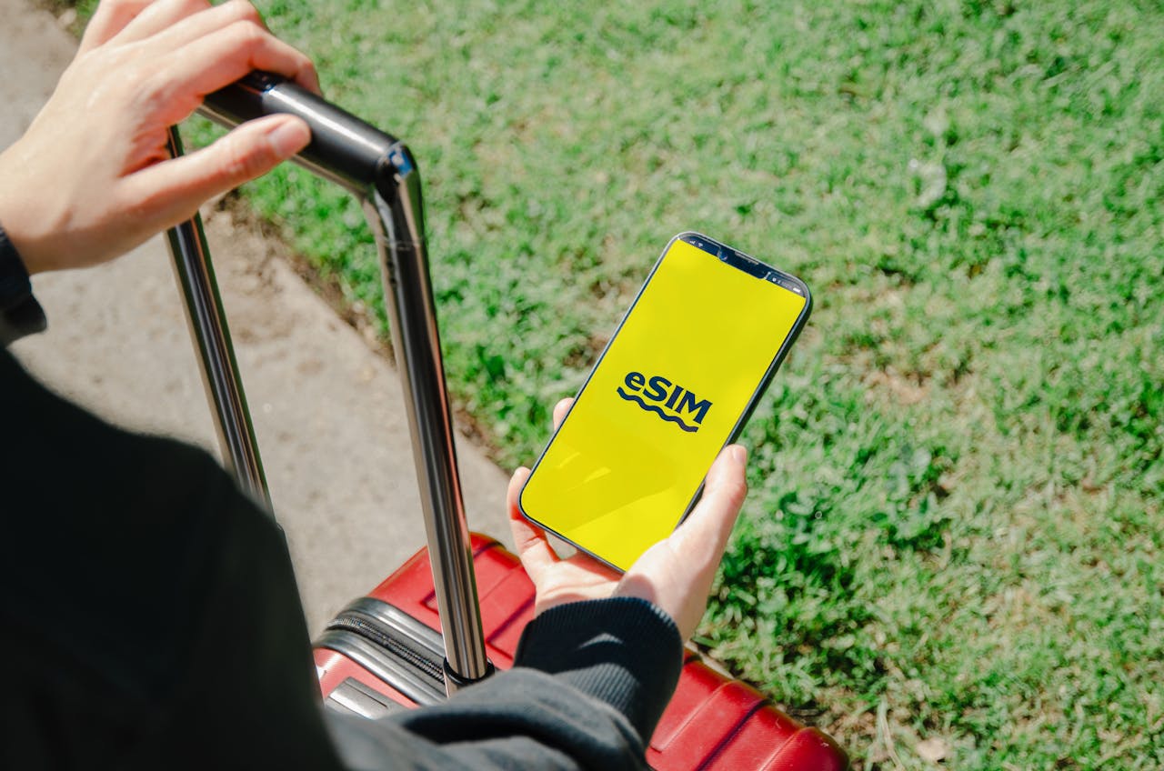 Persona con una maleta de viaje activando una eSIM en la pantalla del móvil