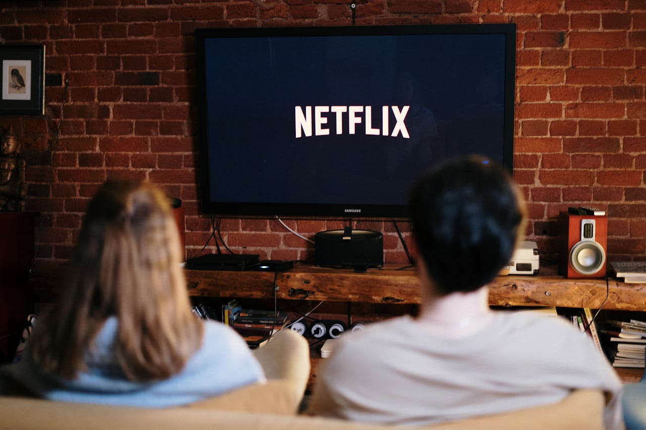 Dos personas en el sofá viendo la pantalla de inicio de Netflix en el televisor del salón